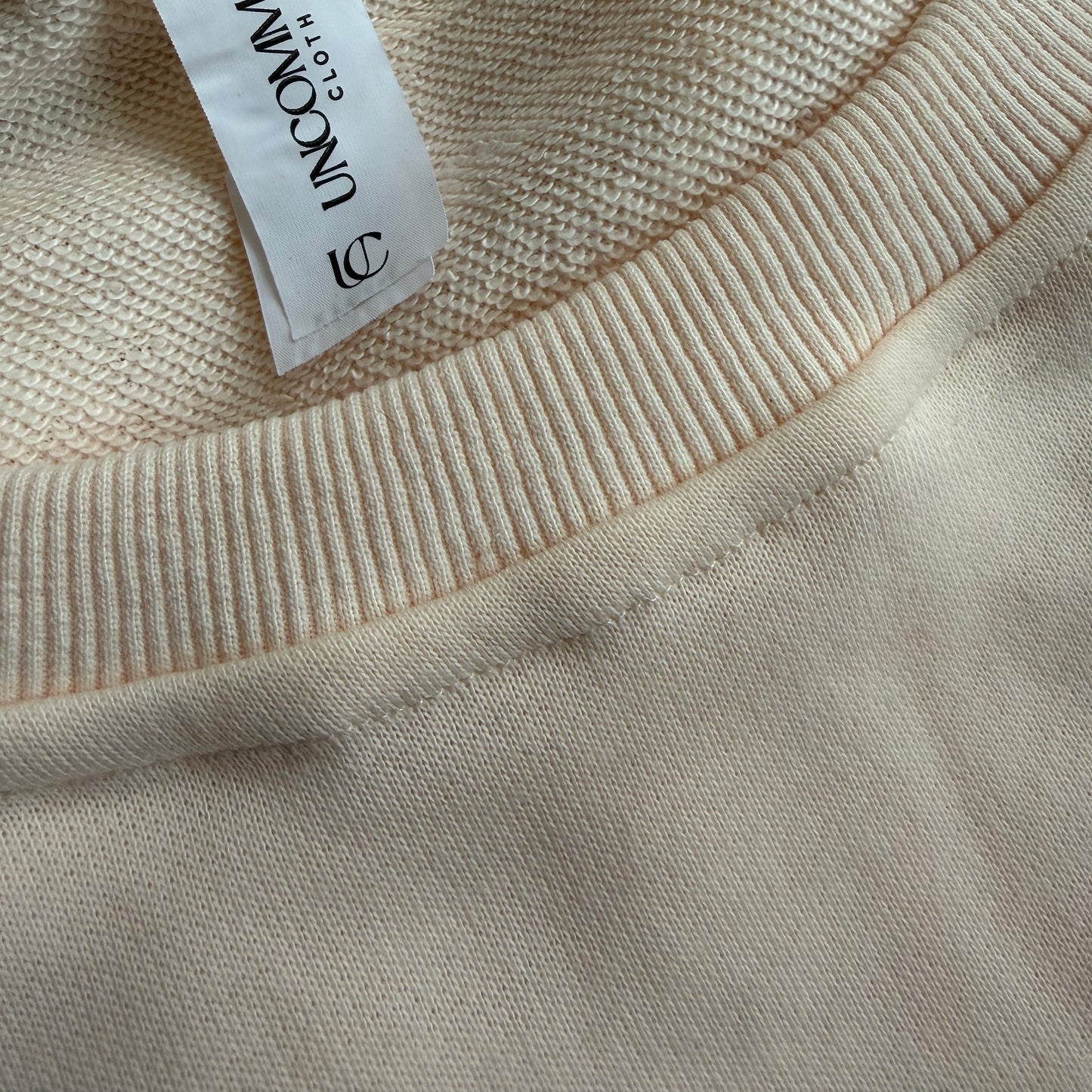 Close-up of beige fabric with a brand tag on a beige background