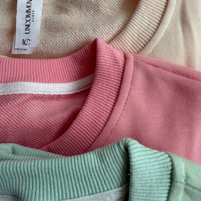Close-up of a sweater with a brand tag on a pink and green fabric background