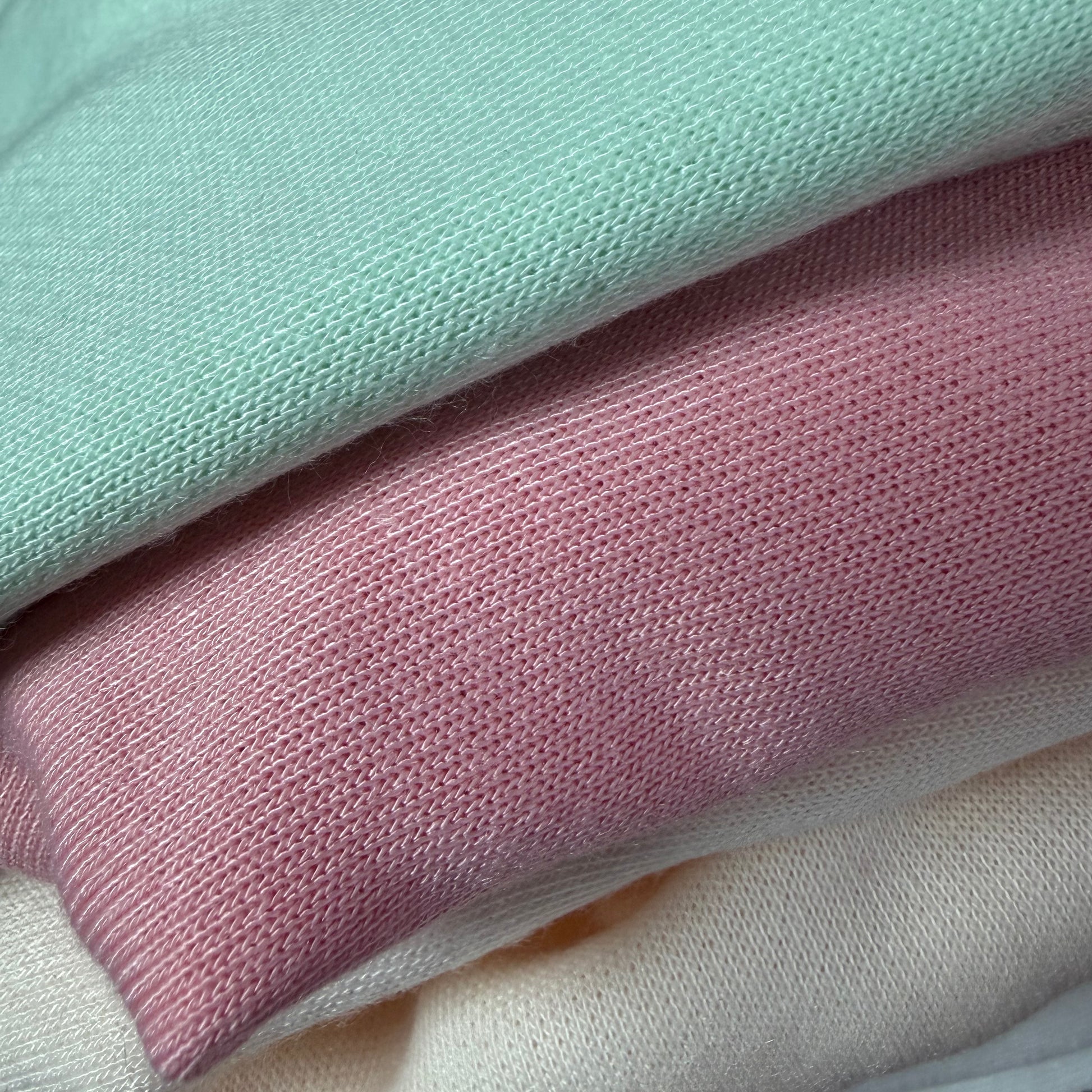 Close-up of pastel-colored textured fabrics stacked on top of each other.